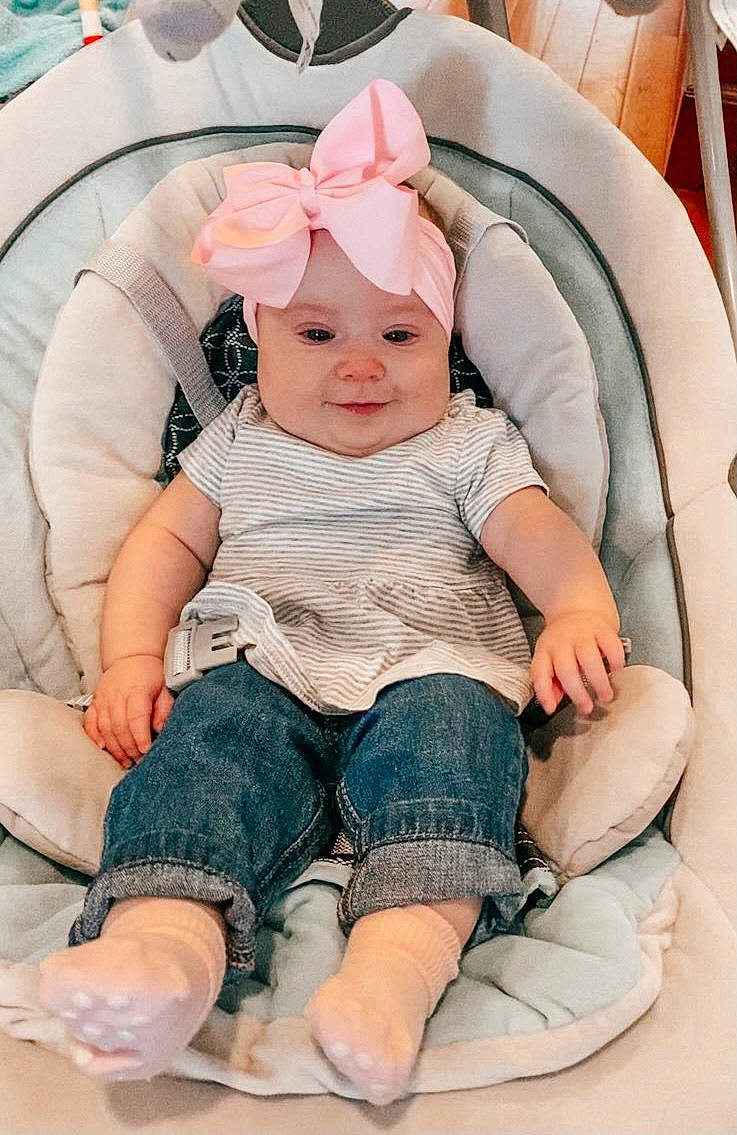 Ivy is registered to the contest to win money with this photo: arm, baby, baby_products, baby_toddler_clothing, cap, chair, cheek, child, comfort, finger, fun, headwear, human, leg, person, pink, product, skin, sleeve, sock