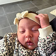 Ava participe au concours pour gagner de l'argent avec cette photo : baby, sleeping, headband, infant, clothing, patterned_clothing, leopard_print, hand, face, closed_eyes, indoors, floor_tiles, couch, comfort, cute, peaceful, portrait, child, soft_lighting, cozy