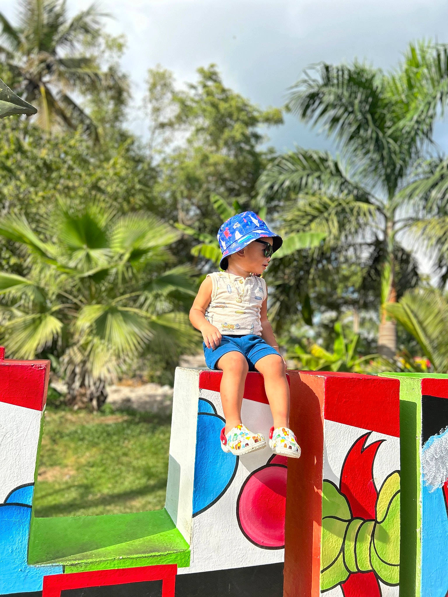 Neymar is registered to the contest to win money with this photo: arecales, city, fun, grass, happy, hat, headwear, human_leg, leisure, palm_tree, people_in_nature, person, plant, recreation, shorts, sky, toddler, tourism, travel, tree