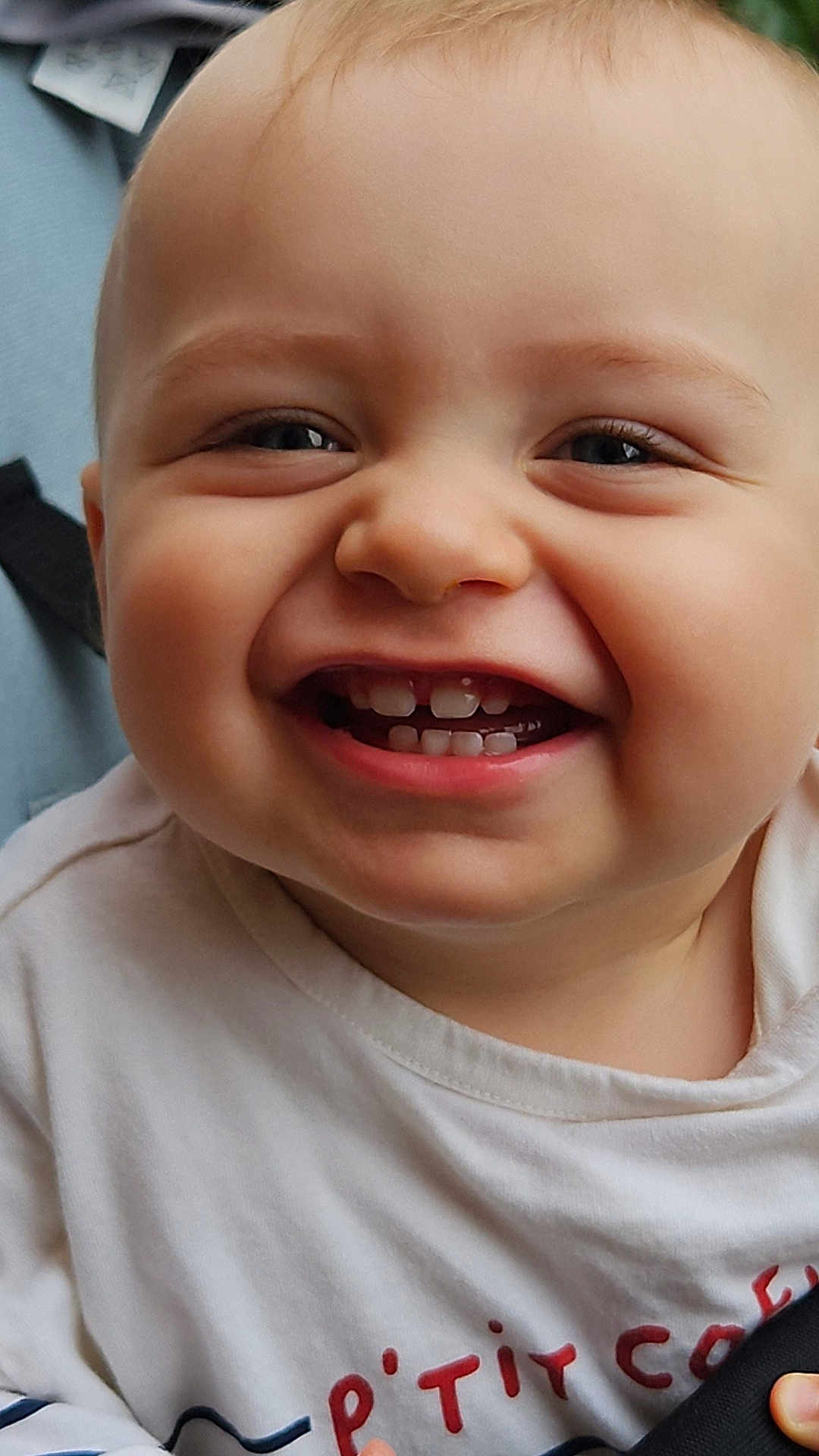 Ardyan a rejoint le concours — aidez-le/la à gagner de superbes lots ! baby, smiling, close_up, face, teeth, child, infant, joyful, white_shirt, red_text, chubby_cheeks, happy, cute, portrait, skin, head, eyes, mouth, expression, person
