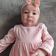 Emy a rejoint le concours — aidez-le/la à gagner de superbes lots ! baby, infant, pink_dress, headband, bow, cute, child, portrait, face, hand, laying_down, indoor, soft_texture, clothing, expression, young_child, person, baby_girl, apparel, headwear