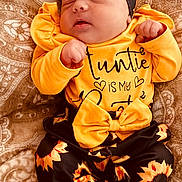 Elodie is registered to the contest to win money with this photo: baby, newborn, sleeping, headband, yellow_clothing, sunflower_pattern, blanket, infant, cute, cozy, soft_texture, child, portrait, resting, peaceful, clothing, patterned_fabric, indoors, small_hands, toddler