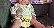 Mikaila joined the competition — help win amazing prizes! baby, infant, child, couch, quilt, patchwork, sign, wooden_sign, three_months, smile, sitting, clothing, long_sleeve, face, feet, legs, indoors, furniture, happy, portrait