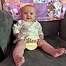 baby, infant, child, couch, quilt, patchwork, sign, wooden_sign, three_months, smile, sitting, clothing, long_sleeve, face, feet, legs, indoors, furniture, happy, portrait
