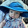 baby, child, infant, blue_hat, floral_dress, blanket, car_interior, steering_wheel, seat, face, eyes, cute, portrait, clothing, person, young_child, sitting, headwear, baby_girl, indoors