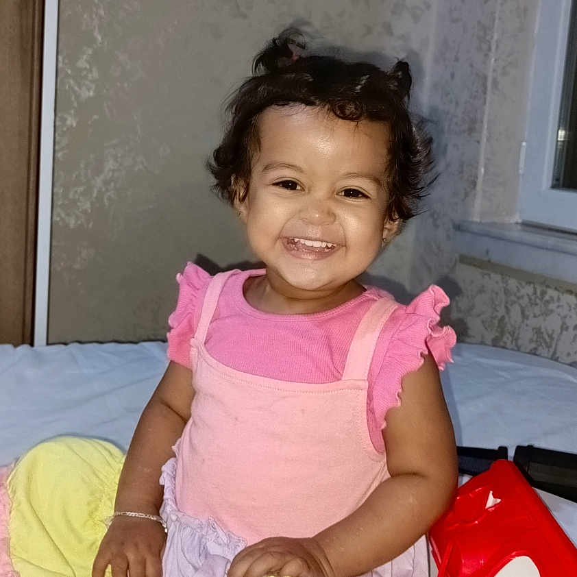 Azra Altıntaş a rejoint le concours — aidez-le/la à gagner de superbes lots ! bed, child, cute, dress, girl, happy, indoor, person, pigtails, pink, playful, portrait, red_toy, sitting, smiling, toddler, toy, wall, window, yellow