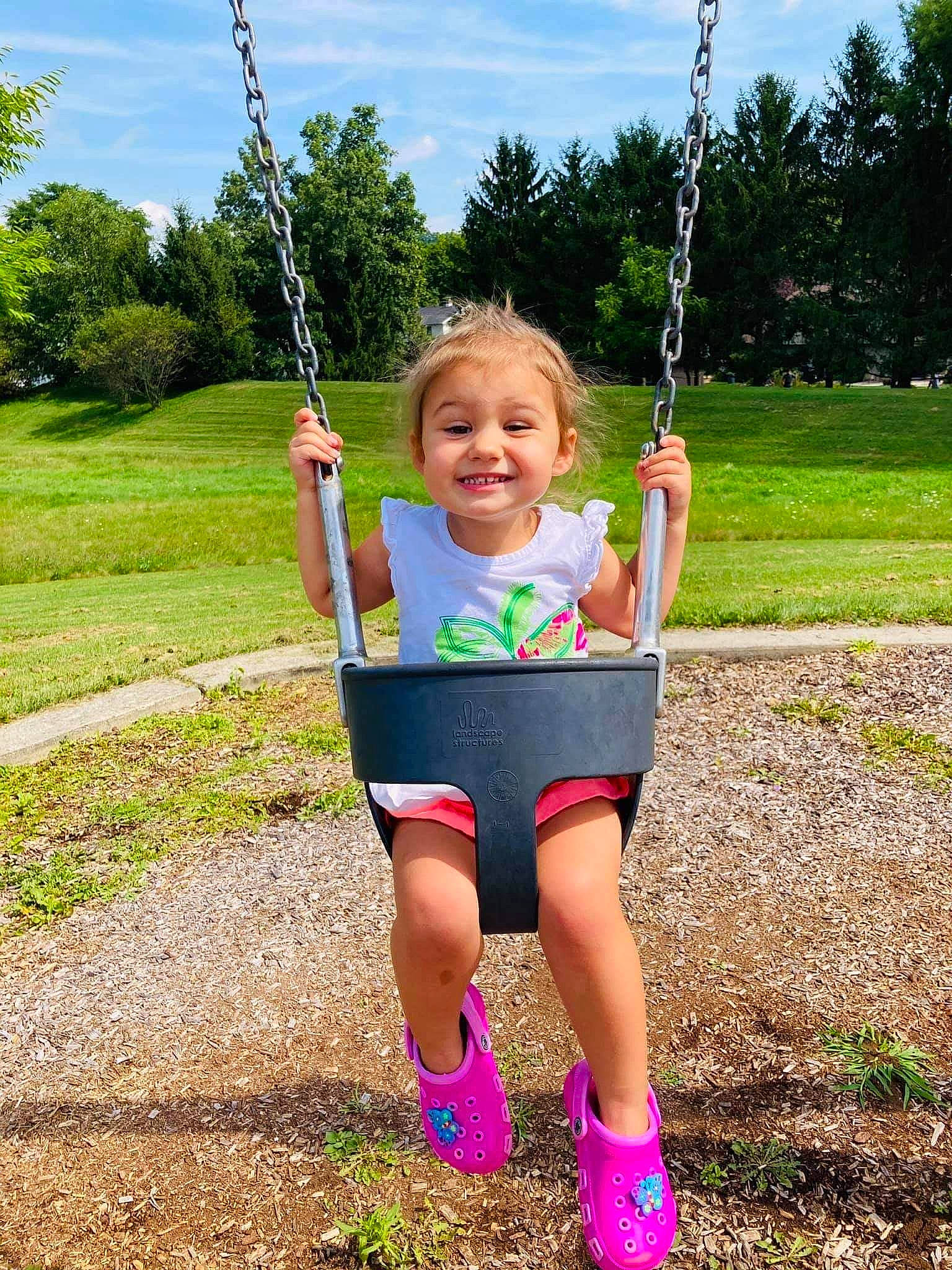 Isabelle is registered to the contest to win money with this photo: child, fun, joy, leisure, outdoor_play_equipment, person, play, playground, public_space, recreation, smile, style, summer, swing, toddler, tree, vacation