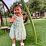 toddler, child, playground, dress, green_grass, smiling, happy, outdoor, summer, sandals, nature, trees, play_equipment, curved_pole, flower_pattern, person, cute, young_child, park, fun