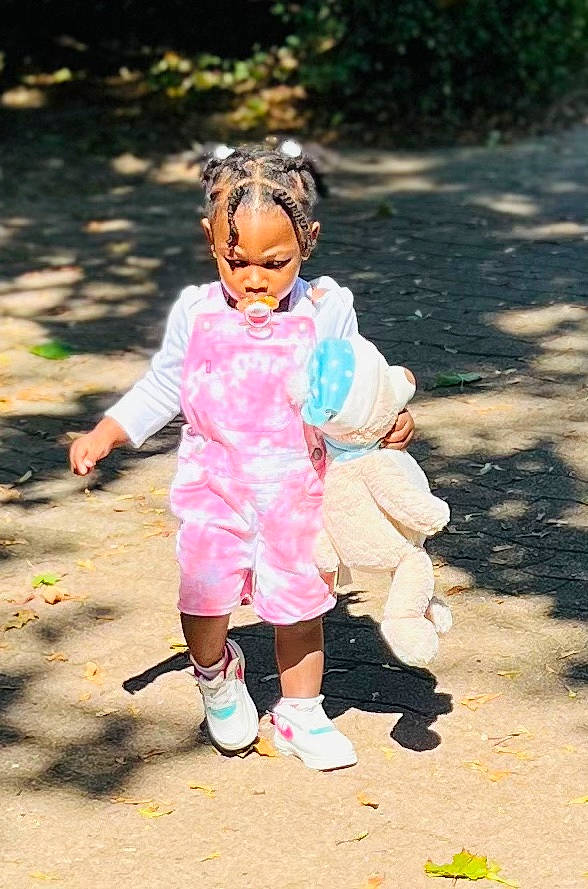 Léah a rejoint le concours — aidez-le/la à gagner de superbes lots ! asphalt, child, face, fun, gesture, grass, happy, leisure, people_in_nature, person, pink, plant, recreation, road, sitting, smile, sneakers, toddler, tree, walking