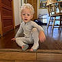 Cyprus is registered to the contest to win money with this photo: child, toddler, pajamas, striped_clothing, curly_hair, indoor, wooden_floor, wooden_furniture, chair, painting, door, home_interior, person, floor, step, motion_blur, cozy, room, casual, young_child