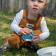 Cyprus is registered to the contest to win money with this photo: child, toddler, curly_hair, blonde, outdoor, grass, easter_eggs, basket, candy, clothing, shoes, fence, sunlight, playing, holding, young_child, casual_wear, nature, daylight, expression