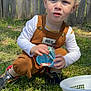child, toddler, curly_hair, blonde, outdoor, grass, easter_eggs, basket, candy, clothing, shoes, fence, sunlight, playing, holding, young_child, casual_wear, nature, daylight, expression