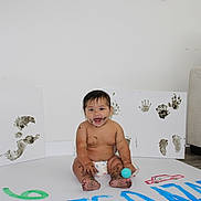 Rodrigo joined the competition — help win amazing prizes! baby, child, diaper, paint, handprints, footprints, canvas, smile, messy, indoor, floor, ball, white_wall, art, playful, sitting, happy, person, cute, expression