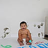 baby, child, diaper, paint, handprints, footprints, canvas, smile, messy, indoor, floor, ball, white_wall, art, playful, sitting, happy, person, cute, expression