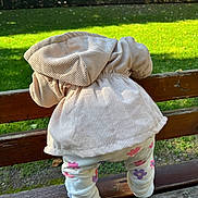 Maria participe au concours pour gagner de l'argent avec cette photo : toddler, child, jacket, hoodie, leggings, floral_pattern, bench, wood, outdoor, grass, park, nature, daylight, greenery, autumn, tree, person, back_view, clothing, baby