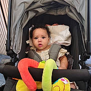 Maria participe au concours pour gagner de l'argent avec cette photo : baby, stroller, blanket, soft_toy, colorful, curly_hair, infant, child, seat_belt, fabric, indoors, person, cute, expression, comfort, sitting, playful, closeup, head, portrait