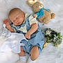 baby, sleeping, plush_toy, bunny, blue_outfit, white_socks, flower_bouquet, soft_blanket, infant, peaceful, cute, child, resting, indoors, adorable, newborn, soft_toys, cozy, portrait, sleep