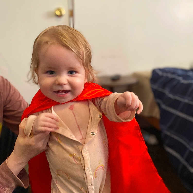 Amelia is registered to the contest to win money with this photo: baby, bodypart, clothing, coat, costume, couch, dress, face, fashion, finger, formalwear, furniture, hand, happy, head, jacket, pants, person, photography, portrait