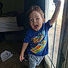 child, boy, toddler, smiling, indoors, portrait, standing, window, sunlight, blue_shirt, shorts, socks, racing_cars, colorful_clothing, open_mouth, raised_arm, happy, bedroom, carpet, daylight