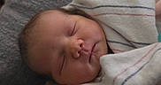 Zoey is registered to the contest to win money with this photo: newborn, baby, sleeping, infant, portrait, face, eyes_closed, swaddled, blanket, swaddle, striped, peaceful, indoors, close_up, resting, cozy, head, skin, nap, photography