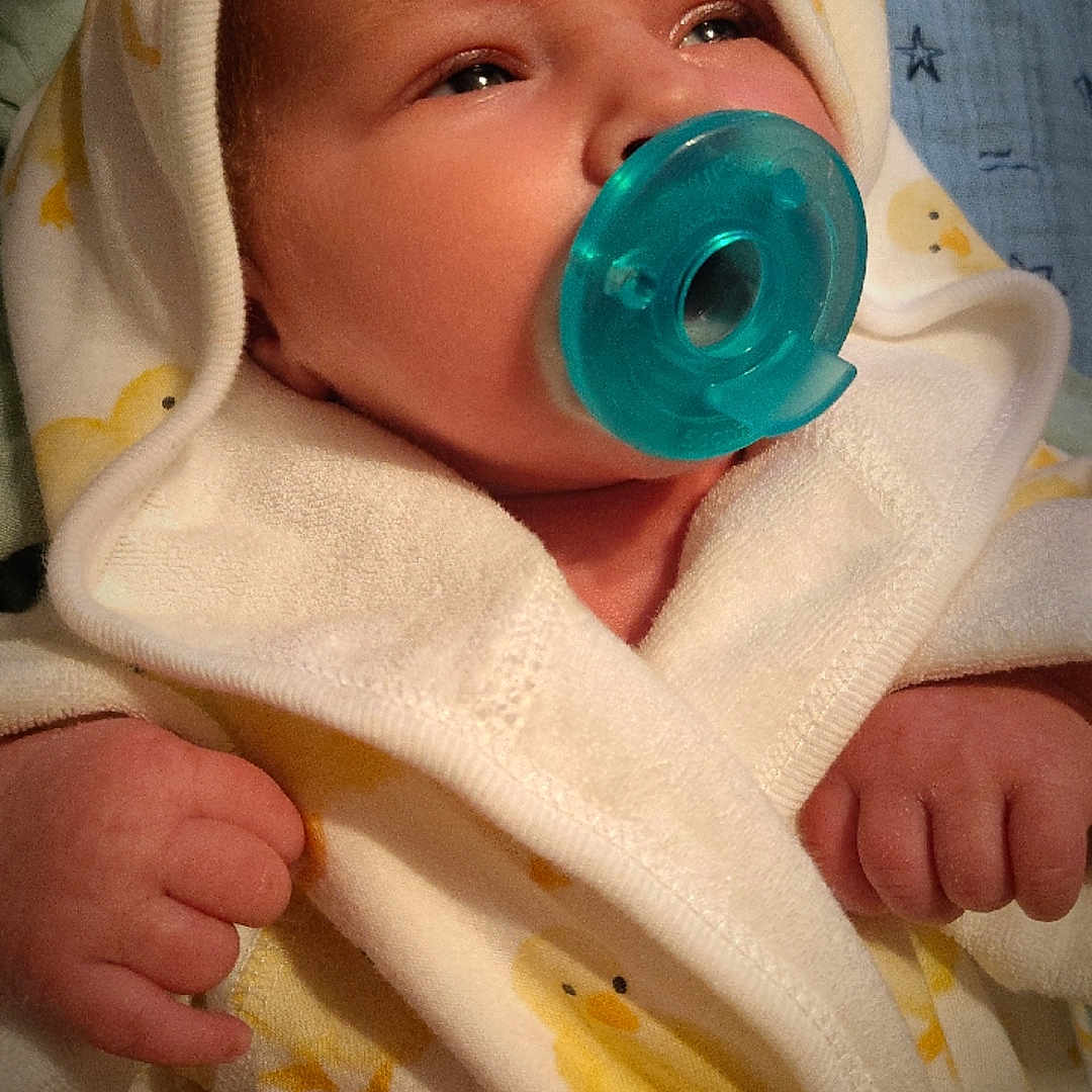 Ryhatt Wayne is registered to the contest to win money with this photo: baby, pacifier, towel, hood, infant, cute, clothing, fist, yellow, blue, pattern, soft, portrait, indoor, newborn, sleepwear, child, face, closeup, warm