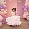 toddler, girl, dress, pink, balloons, butterfly, party, decoration, curly_hair, floor, indoor, smile, child, celebration, cute, happy, event, festive, colorful, portrait