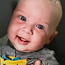 baby, smiling, blue_eyes, close_up, portrait, child, tshirt, sun_graphic, hand, happy, cute, infant, face, skin, expression, cheerful, young, person, clothing, indoors