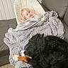 baby, dog, couch, blanket, baby_seat, indoor, pet, fur, sleeping, resting, cozy, home, floor, tile_floor, comfort, child, animal, mammal, relaxation, domestic
