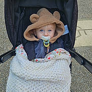 Eugène participe au concours pour gagner de l'argent avec cette photo : baby, stroller, pacifier, blanket, hood, bear_ears, child, outdoor, cute, blue_eyes, clothing, knitted_blanket, person, infant, face, cold_weather, walking, baby_carriage, hooded_jacket, cozy