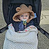 baby, stroller, pacifier, blanket, hood, bear_ears, child, outdoor, cute, blue_eyes, clothing, knitted_blanket, person, infant, face, cold_weather, walking, baby_carriage, hooded_jacket, cozy