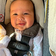 Ralph is registered to the contest to win money with this photo: baby, smile, car_seat, infant, pacifier, blanket, clothing, safety_harness, cute, child, face, head_support, closeup, indoor, soft_light, adorable, newborn, happy, toddler, seat