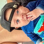 baby, child, face, blue_eyes, hat, cap, hand, fingers, clothing, sitting, person, leg, skin, cute, portrait, indoor, child_wearing_hat, closeup, curious, infant