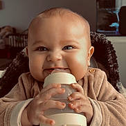 Milo participe au concours pour gagner de l'argent avec cette photo : baby, bottle, child, clothing, cozy, cute, face, feeding, hands, high_chair, indoor, infant, light, mischievous, person, portrait, sitting, smile, warm, young