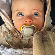 Maïly a rejoint le concours — aidez-le/la à gagner de superbes lots ! baby, infant, pacifier, blue_eyes, hood, blanket, coat, closeup, portrait, rosy_cheeks, lashes, pacifier_clip, fabric, plush, baby_clothes, comfort, cute, sitting, indoors, toddler_accessory