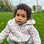 toddler, child, grass, outdoor, jacket, curly_hair, sneakers, playground, swing, leggings, expression, candid, cute, nature, squatting, person, daylight, park, clothing, young