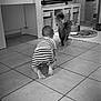 animal, baby, back_view, black_and_white, cat, chair, child, cozy, crawling, curiosity, floor, furniture, home, indoor, pet, play, storage_bins, striped_shorts, table, tiled_floor