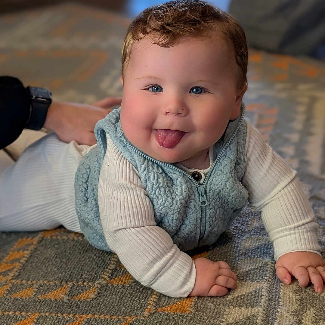 Asher is registered to the contest to win money with this photo: adult, baby, bodypart, clothing, face, finger, hand, happy, head, knitwear, male, man, pants, person, photography, portrait, sitting, smile, sweater, wristwatch