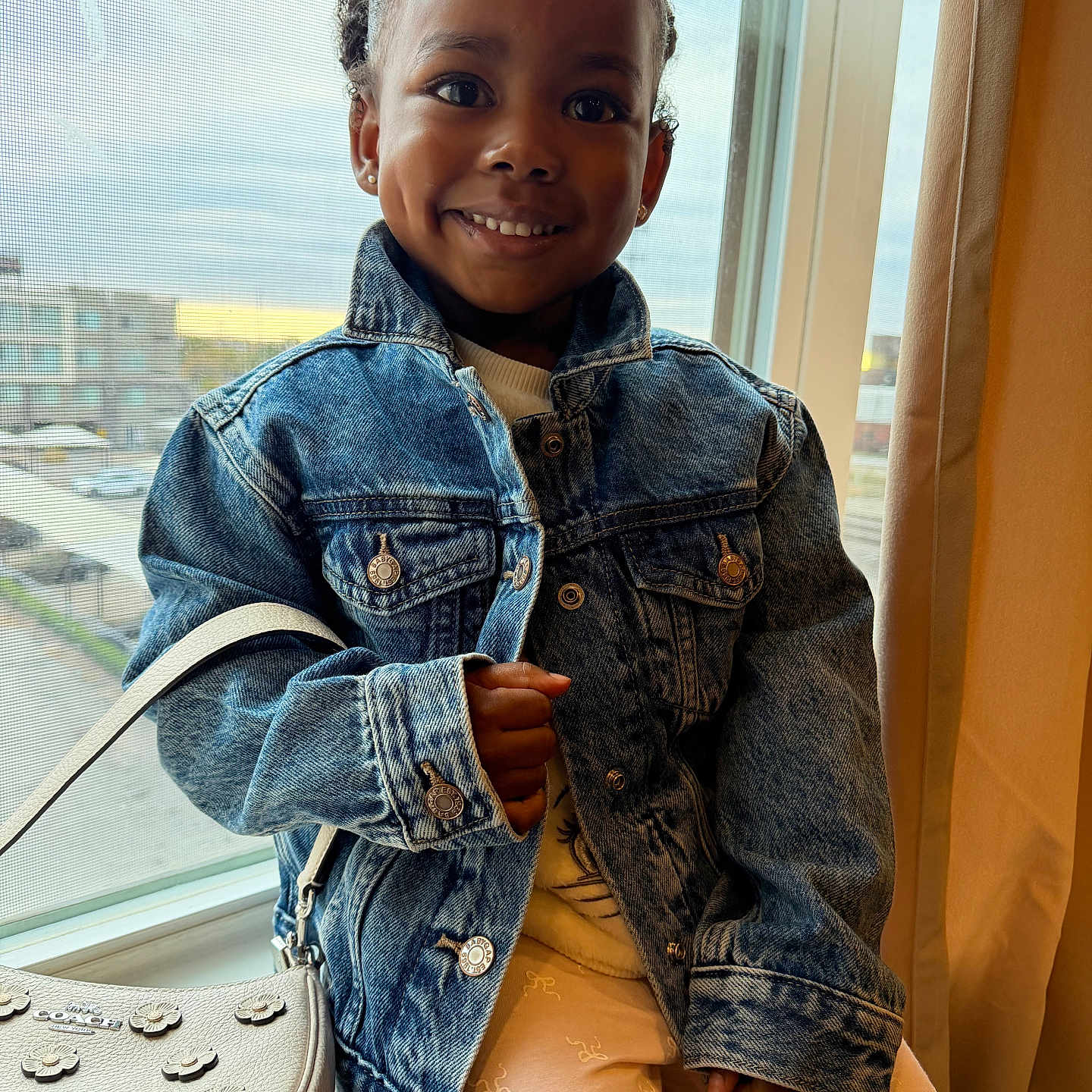 Zayda joined the competition — help win amazing prizes! accessory, child, curtain, cute, daylight, denim_jacket, dimple, face, fashion, happy, indoor, pants, person, portrait, purse, screen, seated, smile, urban, window
