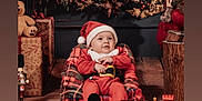 Isaac participe au concours pour gagner de l'argent avec cette photo : baby, child, santa_hat, red_clothing, plaid, bean_bag, christmas_decorations, gifts, teddy_bear, toy_train, wooden_floor, window, snow, holiday, festive, indoor, portrait, smile, cute, cozy