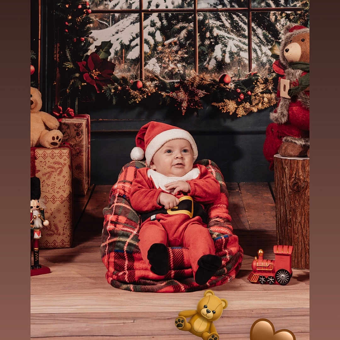 Isaac participe au concours pour gagner de l'argent avec cette photo : baby, bean_bag, child, christmas_decorations, cozy, cute, festive, gifts, holiday, indoor, plaid, portrait, red_clothing, santa_hat, smile, snow, teddy_bear, toy_train, window, wooden_floor