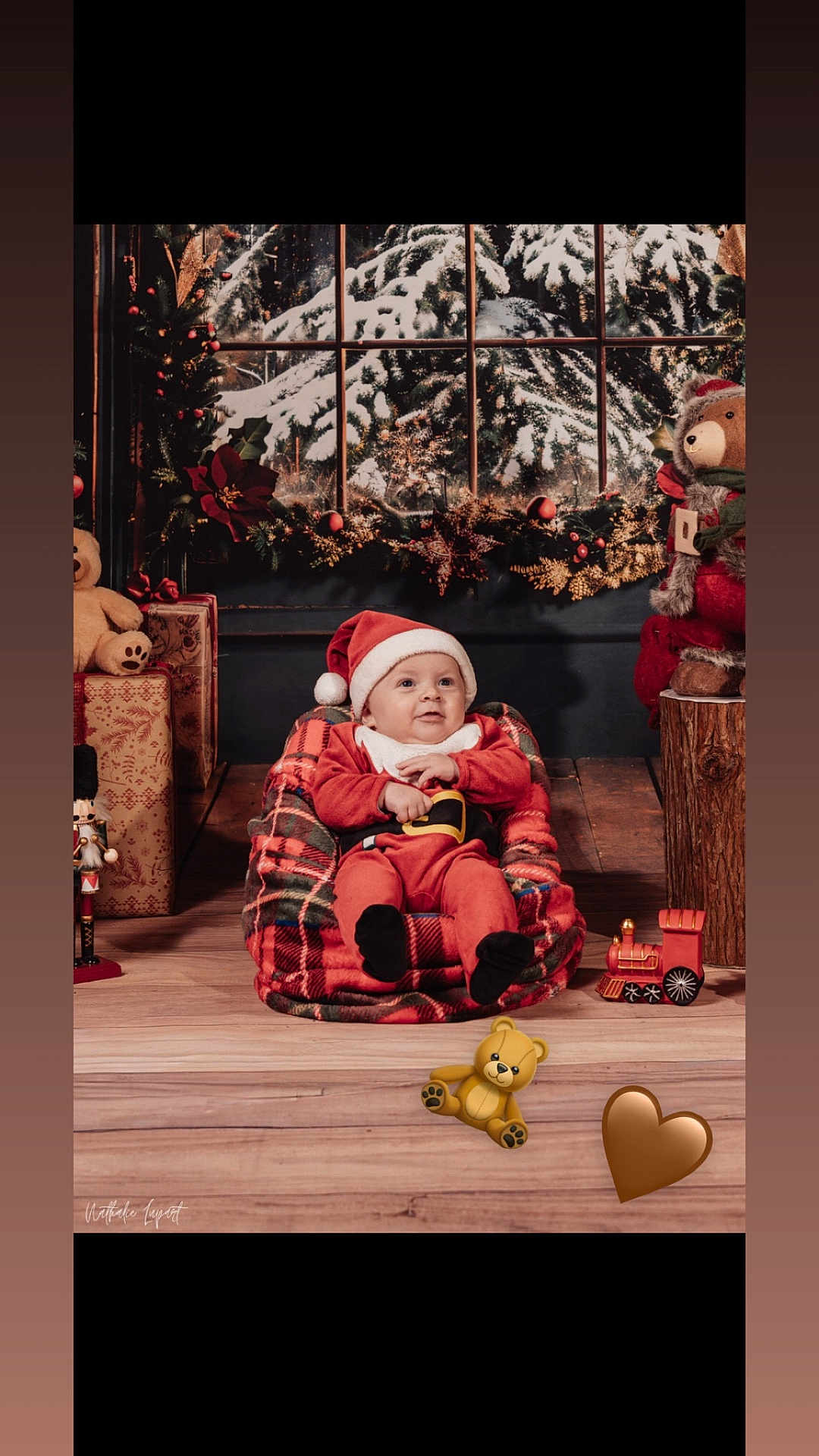 Isaac participe au concours pour gagner de l'argent avec cette photo : baby, child, santa_hat, red_clothing, plaid, bean_bag, christmas_decorations, gifts, teddy_bear, toy_train, wooden_floor, window, snow, holiday, festive, indoor, portrait, smile, cute, cozy