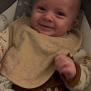 Isaac a rejoint le concours — aidez-le/la à gagner de superbes lots ! baby, smiling, infant, bib, clothing, blanket, seat, cushion, face, person, happy, portrait, hand, indoors, cozy, cute, expression, child, newborn, soft