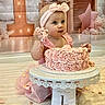 Victoria a rejoint le concours — aidez-le/la à gagner de superbes lots ! baby, birthday, cake, celebration, child, cute, decorations, dress, first_birthday, frosting, happy, headband, indoor, number_one, party, pink, sitting, smiling, table, toddler