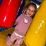 child, smiling, jumping, indoor, playground, inflatable, red, yellow, pink, clothing, peppa_pig, happy, fun, play, kid, person, pants, sweatshirt, toy, activity