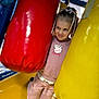 child, girl, playground, punching_bag, red, yellow, pink_clothing, peppa_pig, smile, ribbons, play_area, indoor, fun, kneeling, happy, cute, young, person, play, toy