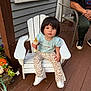 Alina is registered to the contest to win money with this photo: toddler, child, baby_bottle, white_chair, porch, wooden_floor, blue_shirt, patterned_pants, white_shoes, flower_pot, pumpkin, autumn, person, sitting, outdoor, window, plant, casual_clothing, human_face, cute