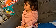 Alina joined the competition — help win amazing prizes! toddler, child, pajamas, sitting, couch, blanket, indoor, clothing, face, hair, person, furniture, diapers, box, relaxed, feet, wooden_floor, home, casual, side_view