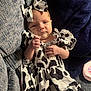 baby, infant, cow_print, dress, headband, bow, couch, blanket, clothing, person, child, cute, indoors, fabric, pattern, resting, small, newborn, skin, portrait