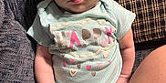 Ava joined the competition — help win amazing prizes! baby, infant, onesie, clothing, sitting, couch, pillow, face, skin, hand, leg, cute, expression, indoors, person, child, young, happy, text_on_clothing, fabric