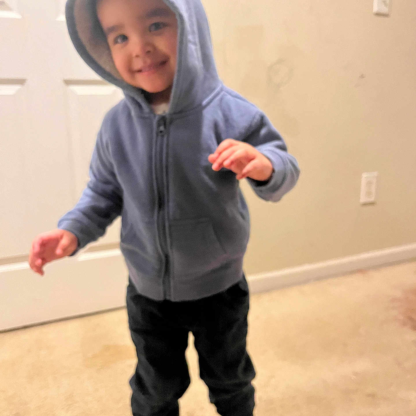 Karson joined the competition — help win amazing prizes! toddler, child, hoodie, blue_clothing, indoor, carpet, door, smile, happy, standing, person, young_child, casual_clothing, pants, white_shoes, wall, light_switch, playful, cute, portrait